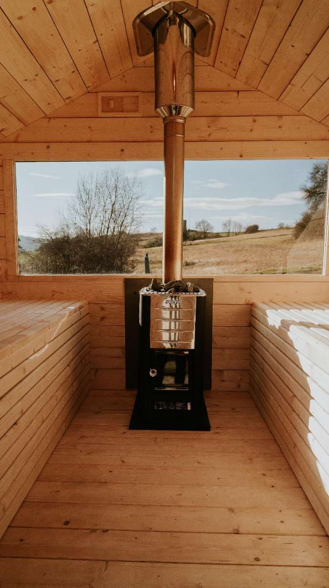Helle Fichtensauna "Honey" von Tiny4You im skandinavischen Design, sichtbare Holzstruktur, Innenraum mit Bänken und Saunaofen